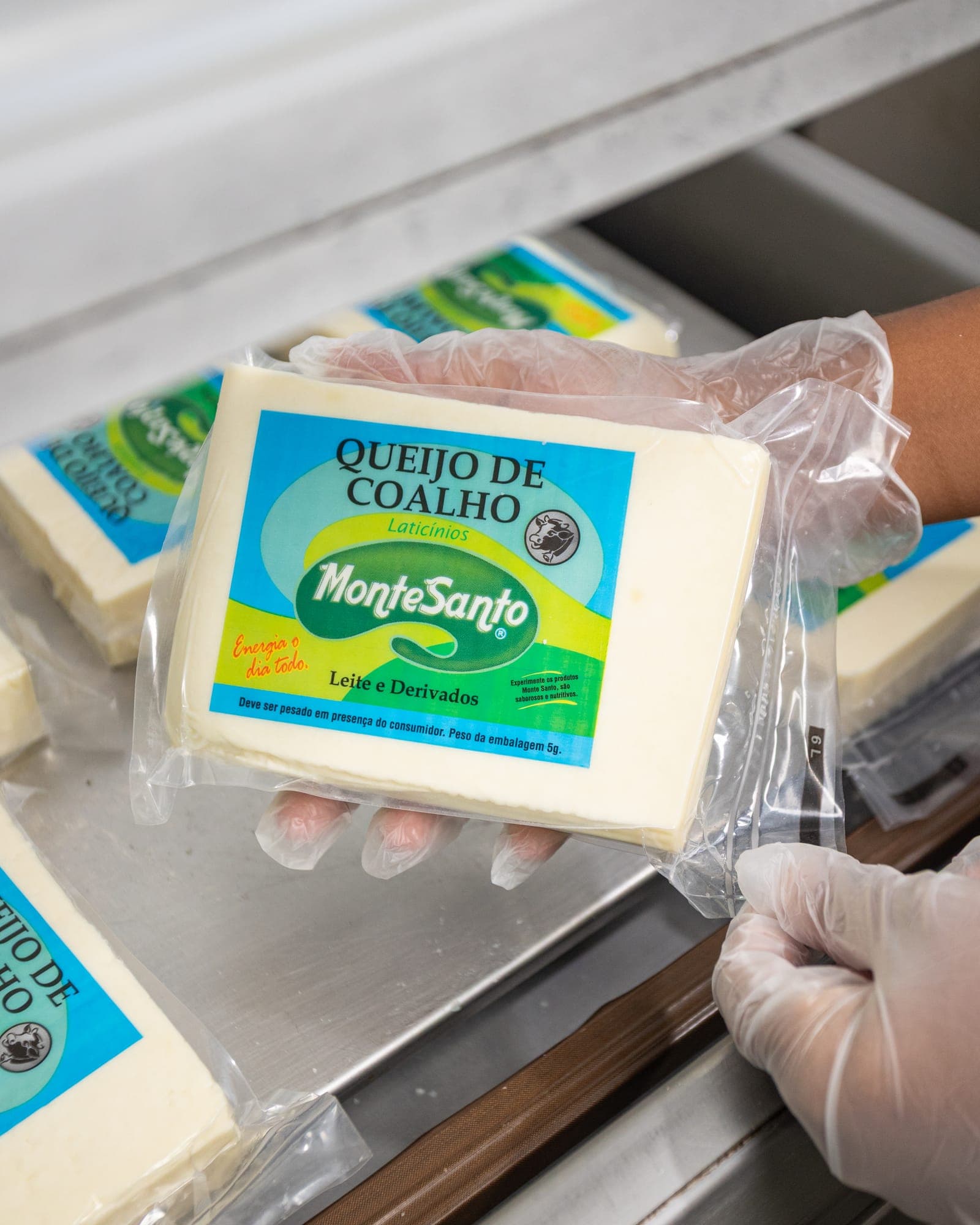 Queijo coalho MonteSanto recém-embalado a vácuo, nas mãos de quem trabalha na fábrica